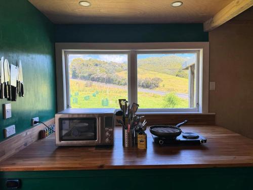 a microwave sitting on a wooden counter with a window at The Woolshed, Papa Aroha, Coromandel in Moturua Island