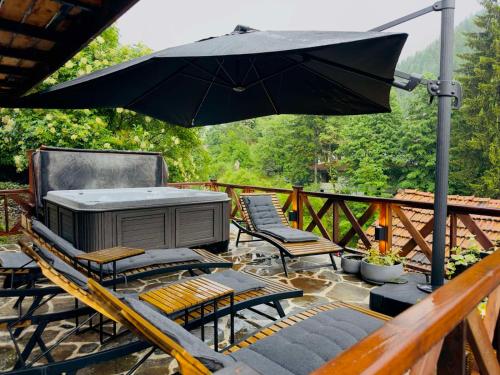 a grill on a deck with chairs and an umbrella at Spa Villa Mezinska Jacuzzi Sauna in Shiroka Lŭka