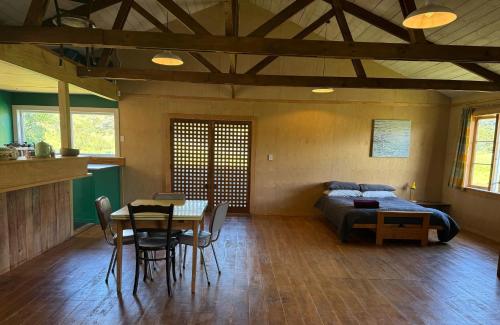 a bedroom with a bed and a table and a tableasteryasteryasteryasteryastery at The Woolshed, Papa Aroha, Coromandel in Moturua Island