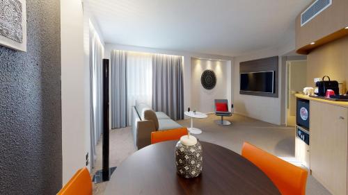 a living room with a table and orange chairs at Novotel Lyon Gerland Musée des Confluences in Lyon