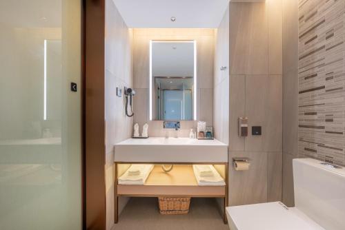 a bathroom with a white sink and a mirror at Lavender Hotel Xinle Shijiazhuang Airport Hebei Academy of Fine Arts in Xinle