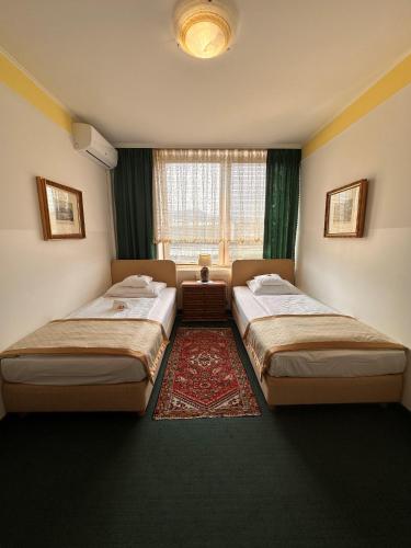 a bedroom with two beds and a window at Hotel Grande in Celje