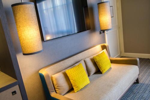a couch with two yellow pillows in a room at Hôtel Alchimy in Albi