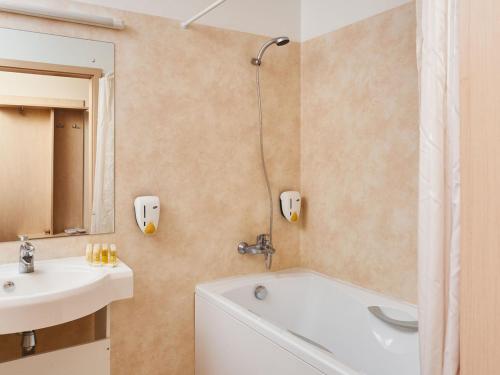 a bathroom with a bath tub and a sink at Rija Bauska Hotel in Bauska