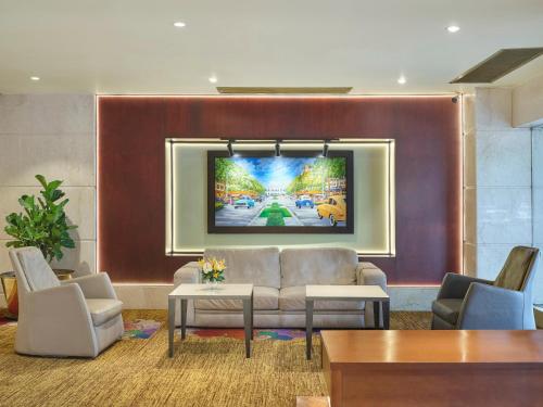 a living room with a couch and a tv on a wall at Palace Hotel Saigon in Ho Chi Minh City
