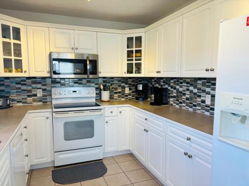 a kitchen with white cabinets and a stove and microwave at Beach Ya There in Holden Beach