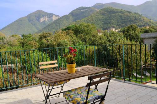 a wooden table with flowers on a balcony with mountains at Casa Fifina Rooms in Sant'Egidio del Monte Albino