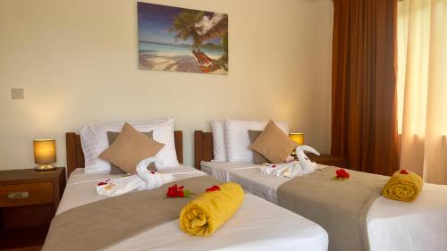 a hotel room with two beds with swans on them at The Palm Seychelles in Bel Ombre