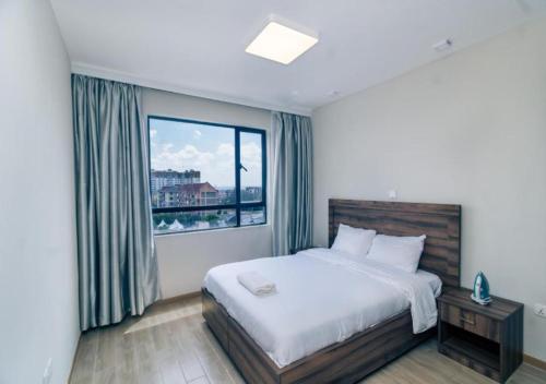 a bedroom with a bed and a large window at JKIA Cosy Apartments by Away Homes Rentals Ltd in Nairobi
