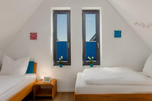 a bedroom with two beds and three windows at Frische Brise in Heiligenhafen