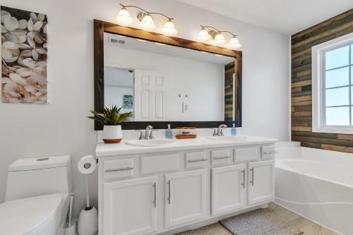 a bathroom with two sinks and a tub and a mirror at Modern 6BR Haven with Playroom, Gym & Deck! home in Cartersville