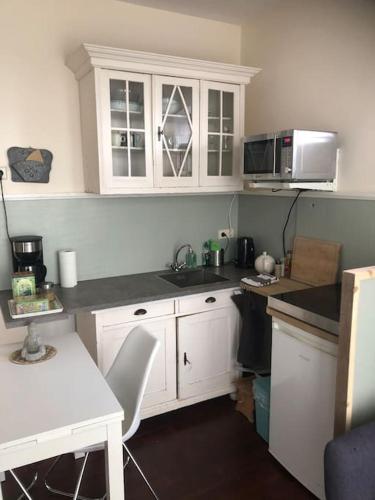 a kitchen with white cabinets and a counter top at Appartement voor twee personen in Twisk