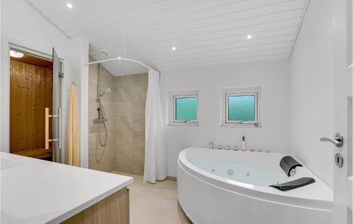 a white bathroom with a tub and a shower at Holiday Home Pramvej Hjørring in Lønstrup