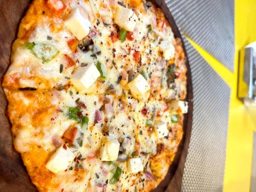a pizza with cheese and vegetables in a box at Lime Tree Hotel - Golf Course Road, Sector-43, Gurugram in Gurgaon