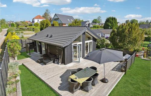 une petite maison avec une table et un parasol dans l'établissement Amazing Home In Faxe Ladeplads With Wifi, à Fakse Ladeplads