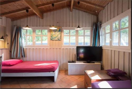 - une chambre avec un lit rouge et une télévision à écran plat dans l'établissement Villa de plage de caractere 12-14 pers CAP FERRET, à Lège-Cap-Ferret