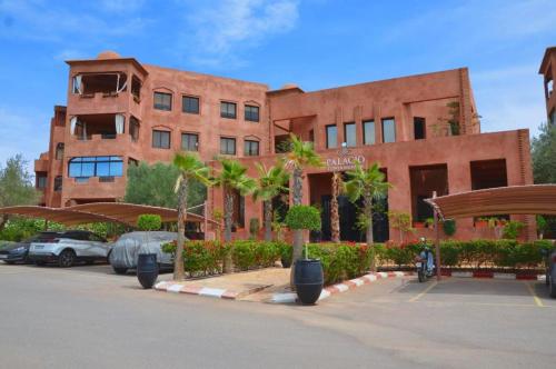 マラケシュにあるPalacio Hôtel Condominium Marrakechの駐車場にヤシの木があるレンガ造りの建物