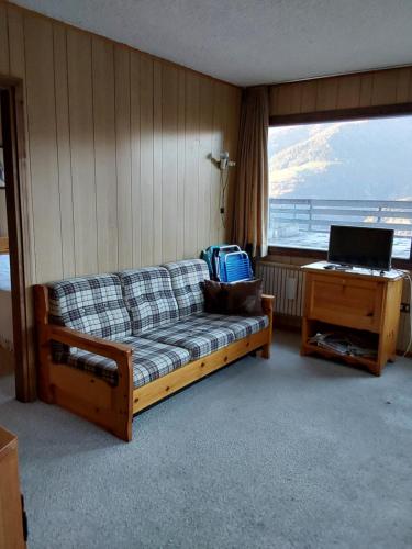 a living room with a couch and a desk with a laptop at lo sguardo sulla valle in Marilleva