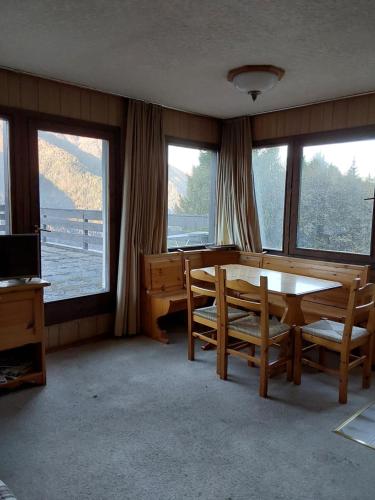 a dining room with a table and chairs and windows at lo sguardo sulla valle in Marilleva