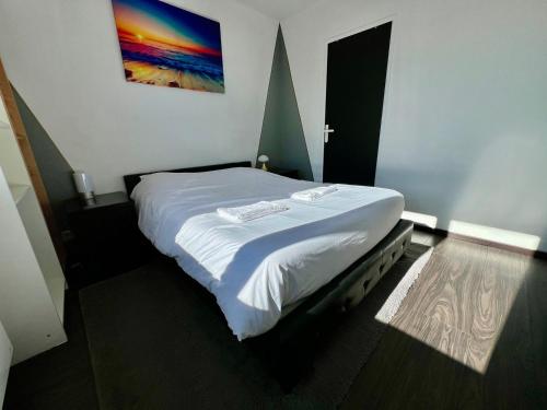 une chambre avec un lit blanc avec un tableau sur le mur dans l'établissement Le Saint-Eloi, à Poitiers