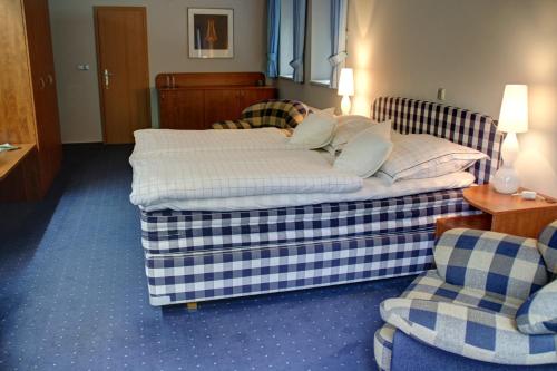 two beds in a hotel room with two chairs at Hotel Břízky in Jablonec nad Nisou