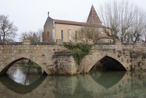 a bridge over a river in front of a church at Les Hirondelles in Fourcès
