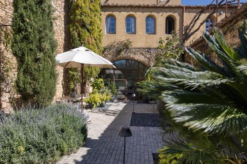 a patio with an umbrella and some plants at Les Hamaques Hotel in Viladamat