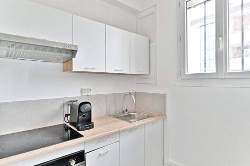 - une cuisine blanche avec un évier et des placards blancs dans l'établissement Studio cosy proche de la capitale - Montreuil - II, à Montreuil