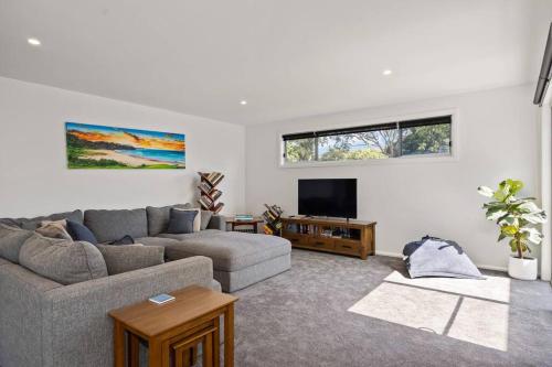 a living room with a couch and a tv at Bawley Beach Escape in Bawley Point