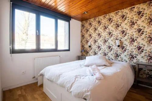 una camera da letto con un grande letto bianco con una finestra di Maison à l'orée du BOIS CITADELLE de LILLE avec TERRASSE en plein sud PROCHE DE TOUTES COMMODITES à la porte de LILLE a Lambersart