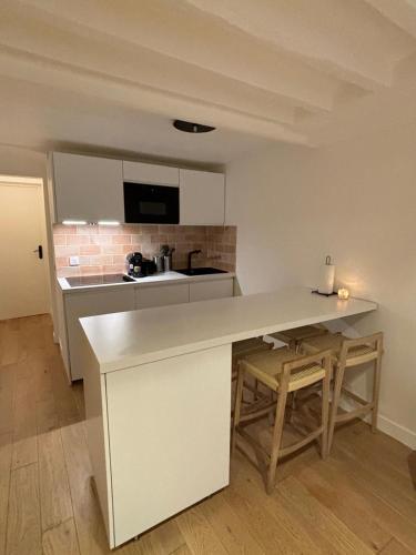 une cuisine avec un comptoir blanc et une table dans l'établissement APPARTEMENT CONTEMPORAIN RÉPUBLIQUE - TEMPLE 2, à Paris
