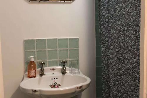 a bathroom with a white sink and a shower curtain at Milk Shed - Couples Seaside Retreat Whitstable in Kent