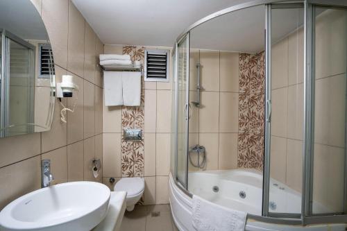 a bathroom with a sink and a tub and a toilet at HALLEY OTEL in Denizli