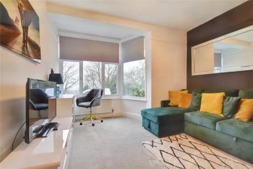 a living room with a green couch and a desk at Kingsdown Apartment in Great Malvern