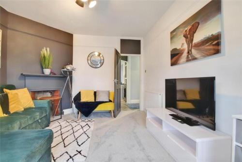 a living room with a green couch and a fireplace at Kingsdown Apartment in Great Malvern