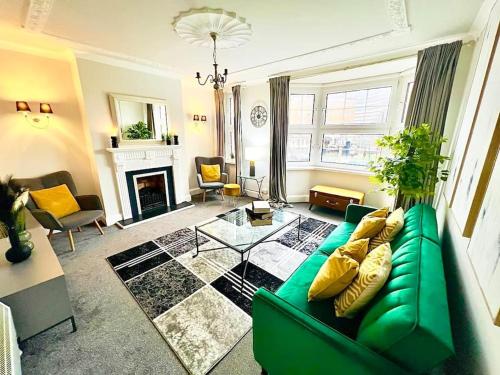 a living room with a green couch and a fireplace at Meadows Court - Wyndale Living - Mansion Style Apt in Birmingham