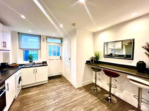 a kitchen with a counter and two bar stools at Meadows Court - Wyndale Living - Mansion Style Apt in Birmingham