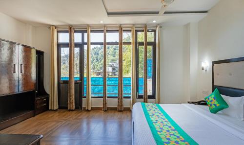 a bedroom with a bed and a tv and some windows at Treebo Anjukul in Dalhousie
