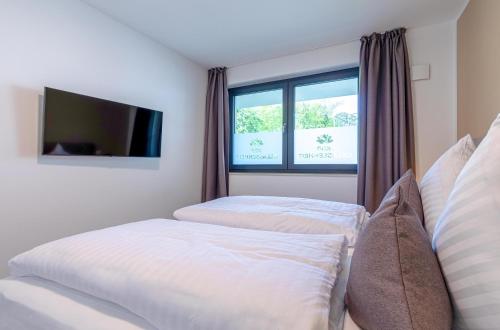 a bedroom with two beds and a tv and a window at Gelassenheit - modernes Apartment am Krakower See in Krakow am See