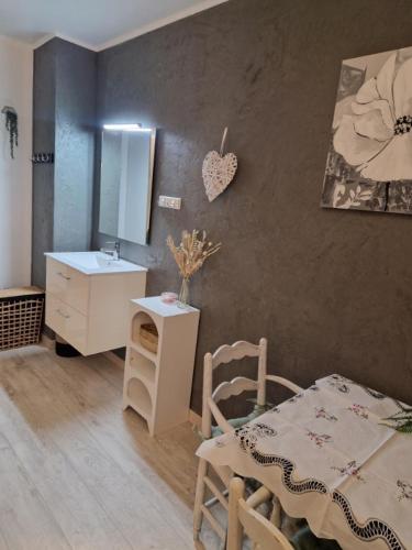 Cette chambre comprend une table, un lavabo et un miroir. dans l'établissement Mes Chambres à la campagne, à Orange