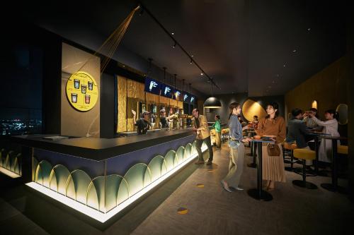 a group of people standing around a bar in a restaurant at OMO Kansai Airport by Hoshino Resorts in Izumi-Sano