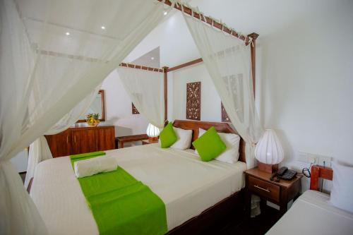 a bedroom with a large bed with green pillows at Lake Wind Resort in Tissamaharama