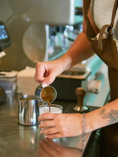 a woman is stirring a drink with a spoon at Sunraf Luxe Apartments in Budva