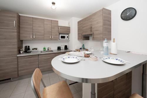 a kitchen with a large white table and wooden cabinets at Tout confort à Massy - Parking / TGV et RER B&C in Massy
