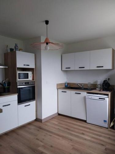 une cuisine avec des armoires blanches et des appareils électroménagers blancs dans l'établissement Maison plain-pied, à Pléaux