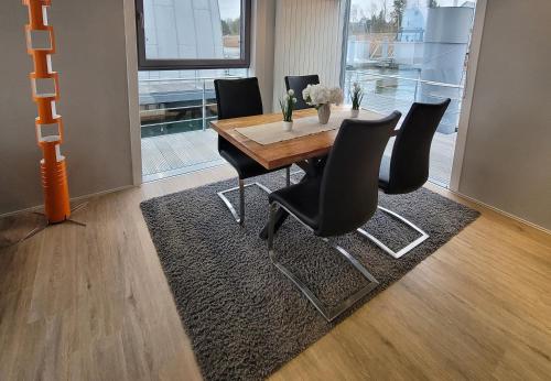 a dining room with a wooden table and black chairs at schwimmende Ferienwohnung Sundowner in Elsterheide