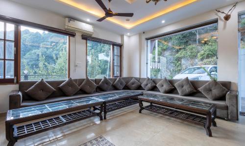 a living room with a couch and large windows at Treebo Anjukul in Dalhousie