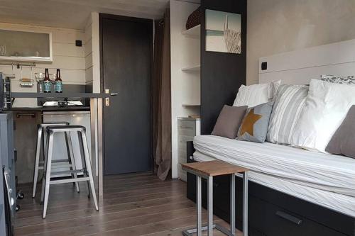 a small room with a bed and a stool and a kitchen at Le cocon de la plage du Santocha in Capbreton