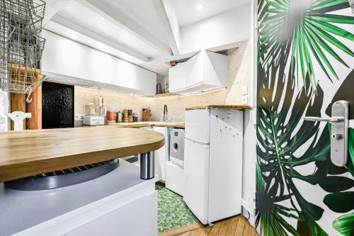 une cuisine avec des armoires blanches et un comptoir en bois dans l'établissement Chambre cosy dans petit loft, à Paris