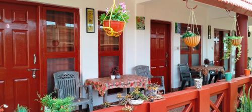 a house with two tables and chairs on the porch at Holidayincoorg - Brick lane in Madikeri